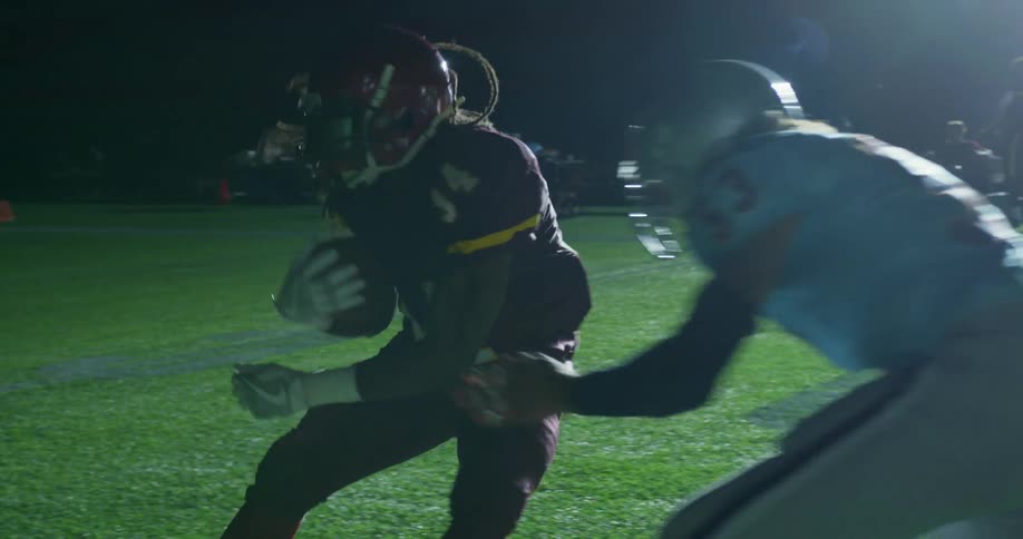 A football player makes a move to avoid a tackle while others look on