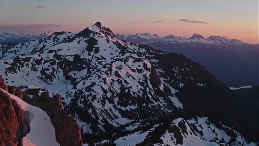 Aerial of a snow covered mountain revealed through rocky spires