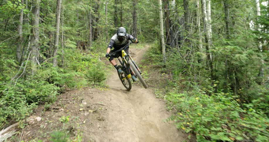 A mountain biker stylishly scrubs bike down a trail in forest