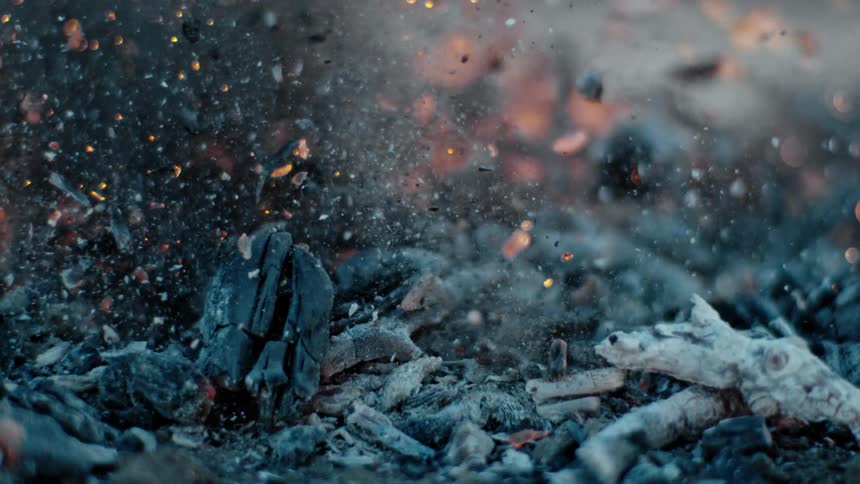 Ashes and embers from an outdoor fire fly into the air