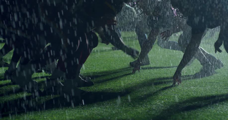 Two football teams square off during a rain storm