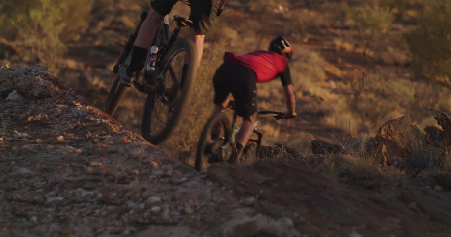 Two people mountain bike down a rocky slab wall ride
