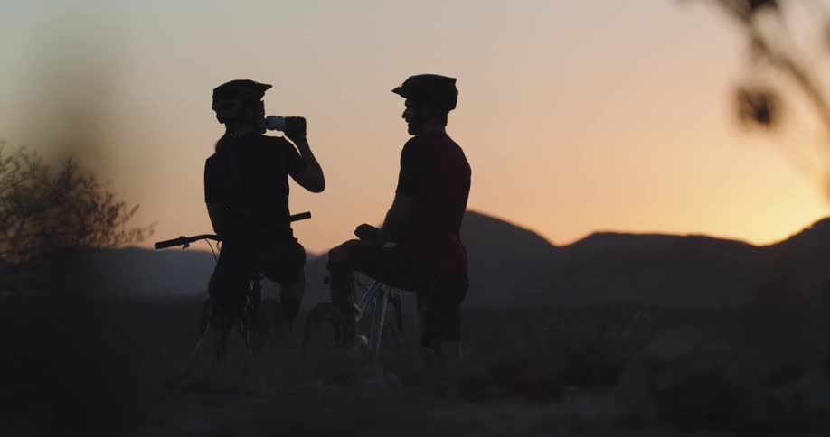A man and woman break after riding bikes with mountains in the background