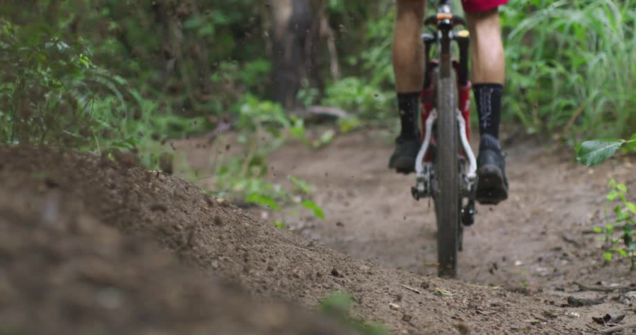 Man on mountain bike kicks up dirt when hitting fast corner