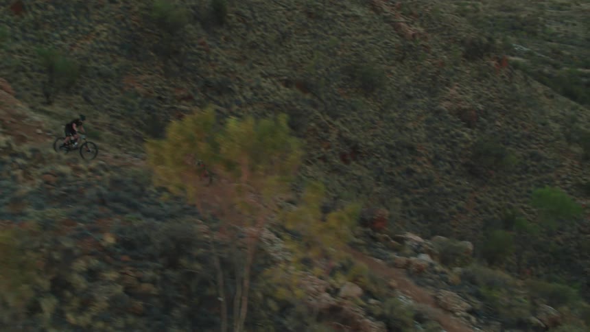 Mountain bikers ride down rugged trail in the evening