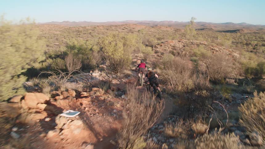 Two people out mountain biking on dirt trail in desert