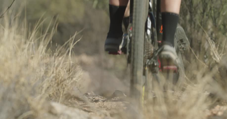 Close-up details of two people mountain biking and jumping down trail