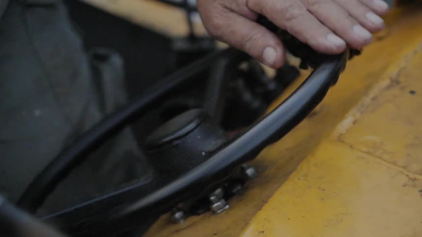 A man operating the steering wheel of a yellow vehicle