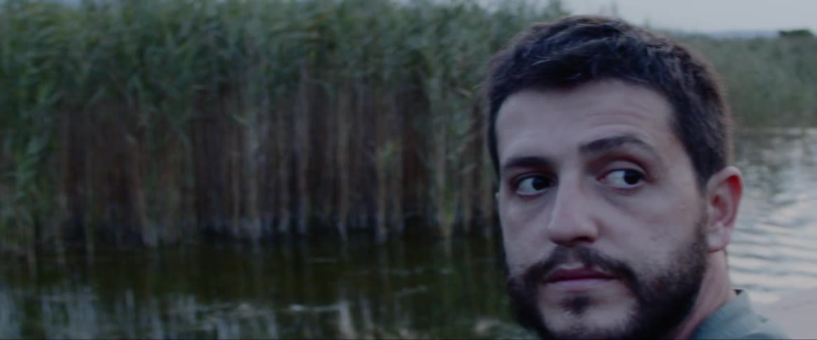 Man with video camera riding on boat through wetlands