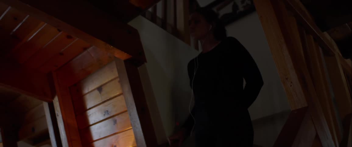A woman solemnly walks down a home staircase