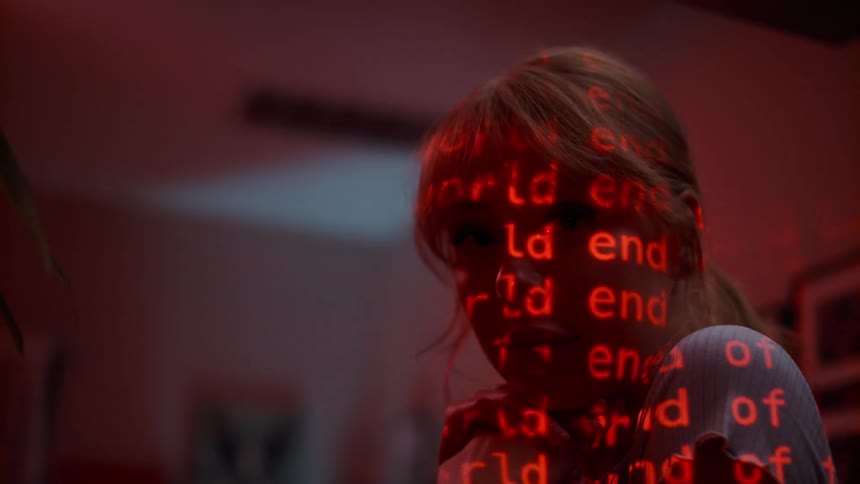 A blonde woman poses in a living room as digitized red text appears over face