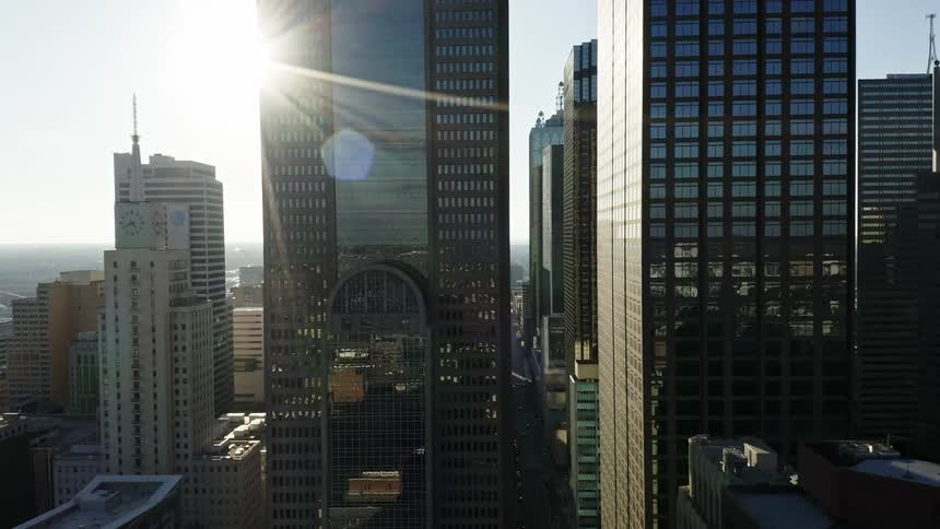 The sun shines off tall skyscrapers with reflective windows