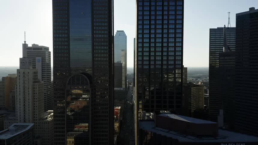Sunlight reflects off the side of several tall shiny skyscrapers