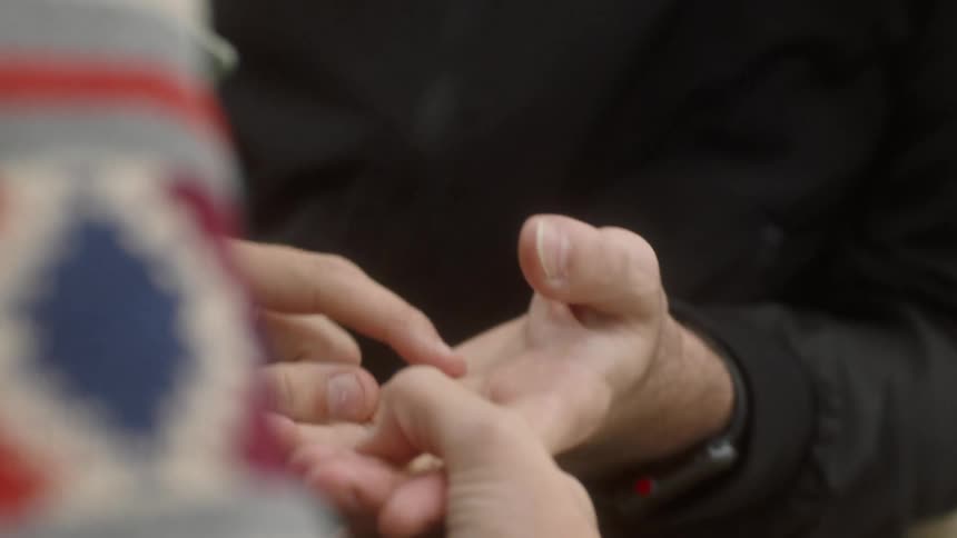 Woman holding mans hand and tracing lines in his palm with her finger