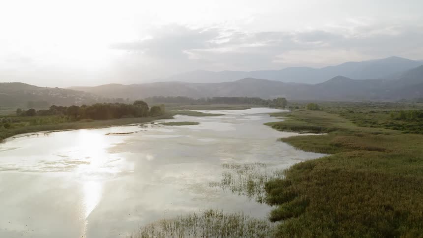 Calm pond sits near the mountains under a cloudy sky