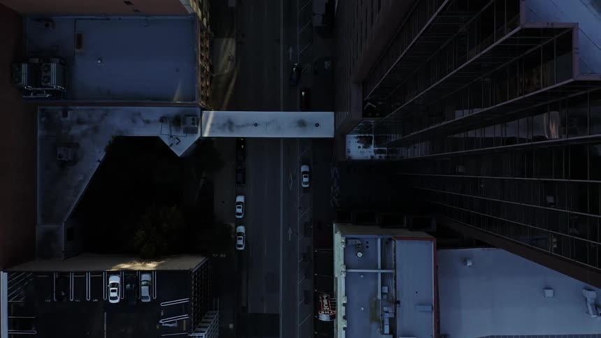 Trucks and cars move down a road in between high rise city buildings