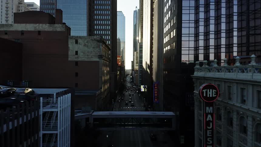 Traffic and pedestrians move down a city street buried deep in a canyon of tall downtown buildings