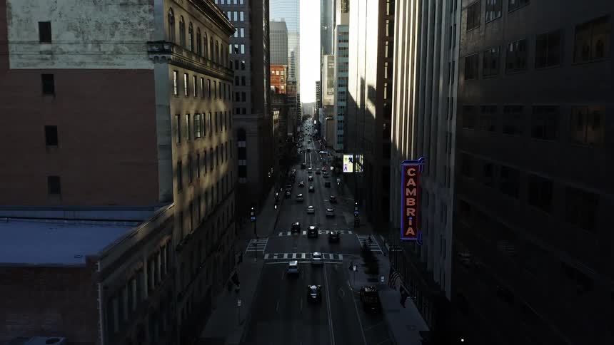 Traffic moves down a street hemmed in by big city buildings