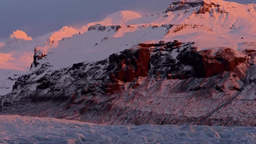 A snow covered mountain is illuminated by the evening sun
