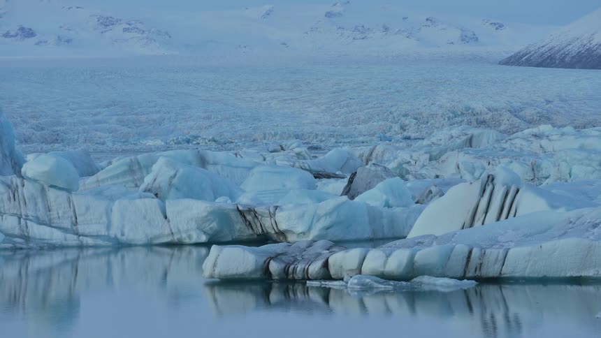 Glacier covers water in front of mountain range