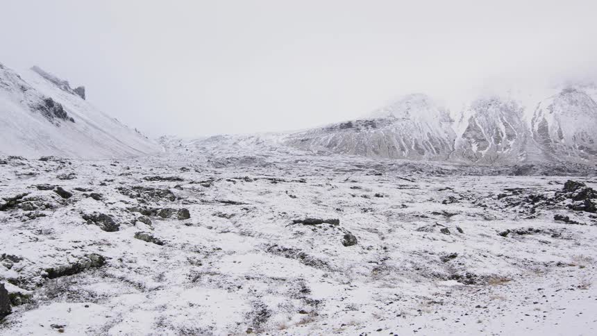 Aerial view of snowy mountains and plains in mid day