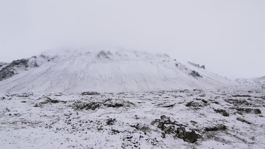 Snow covers rocky ground and a mountain