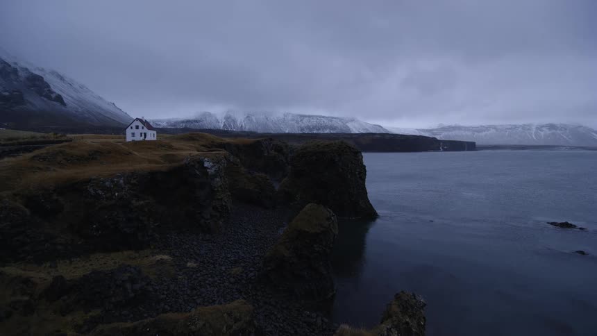 A house is on a ledge near the ocean water