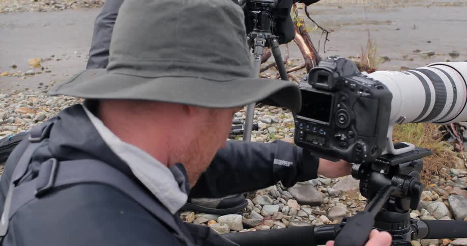 People are setting up and taking photographs by a stream
