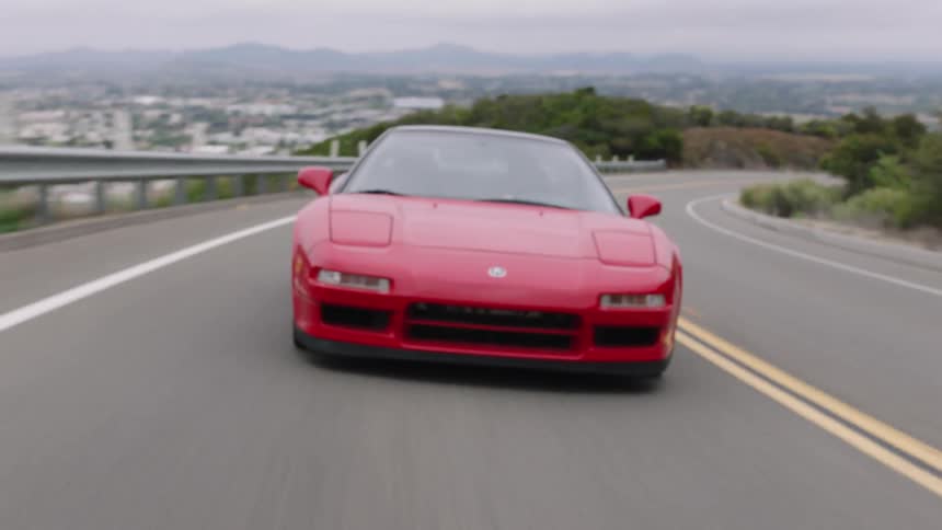 A red sports car travels on a curving road