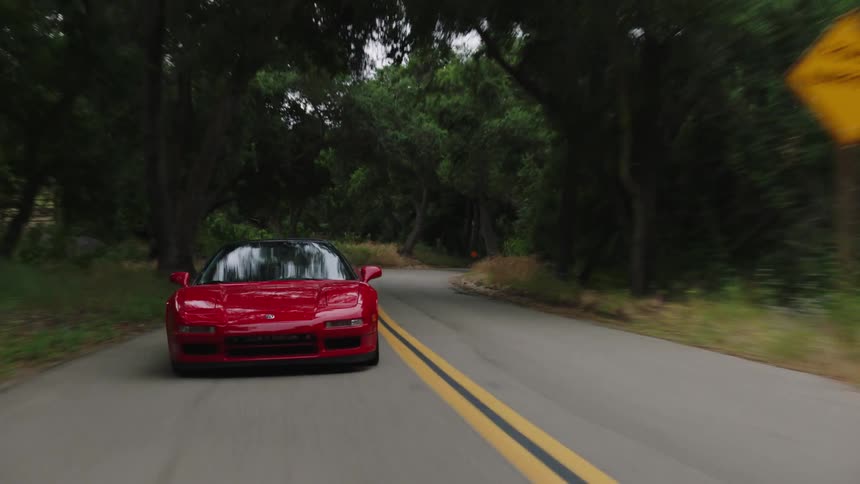 Red sports car driving fast on road through the mountain