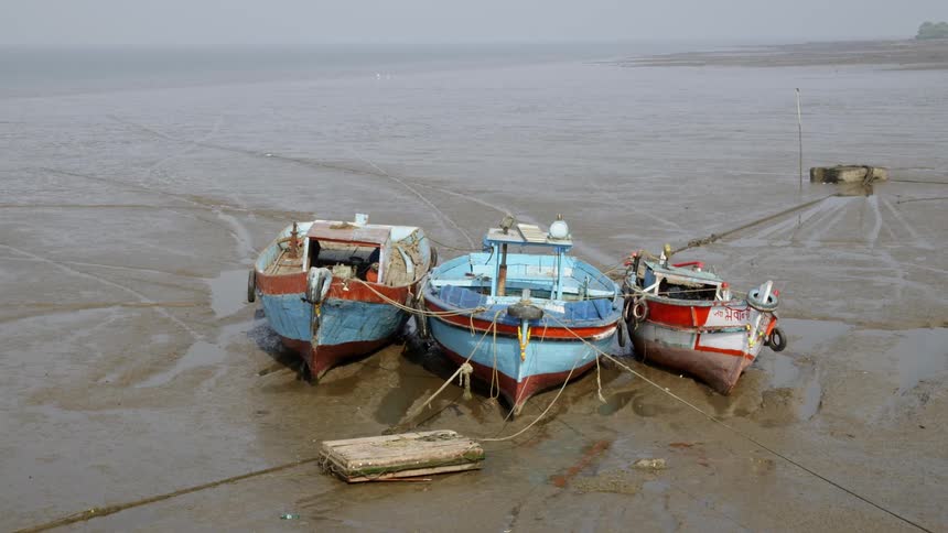 Three boats tied together and stranded on a beach