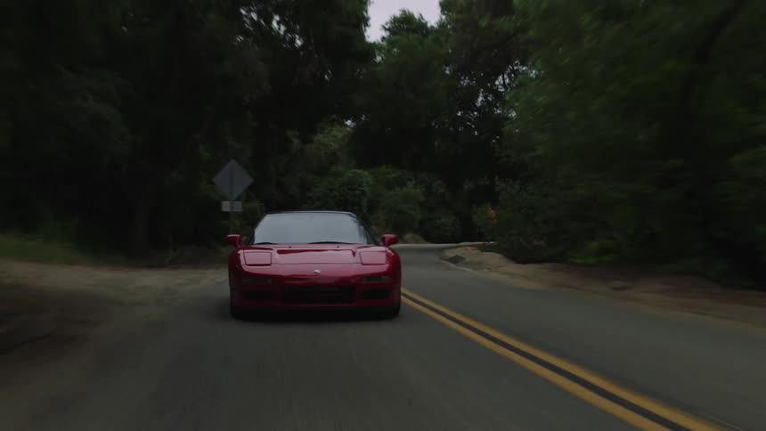 Red sports car driving fast on a windy mountain road