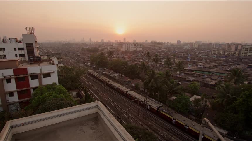 A train traveling down a track through a city under a low sun