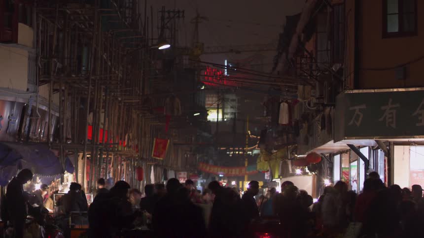 Large crowds move through an asian neighborhood in a city