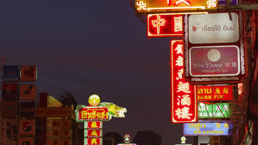 Signs litter the front of store facades in an asian neighborhood in a city
