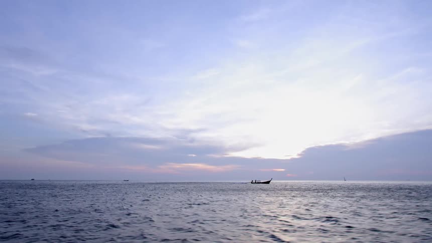 A boat moves across the wide expanse of the ocean