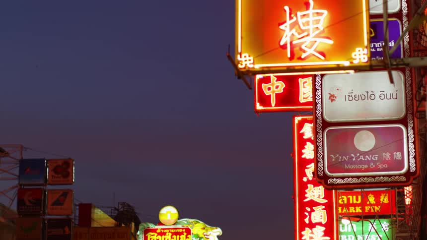 Bright neon signs with text hang outside businesses in an asian neighborhood in the city