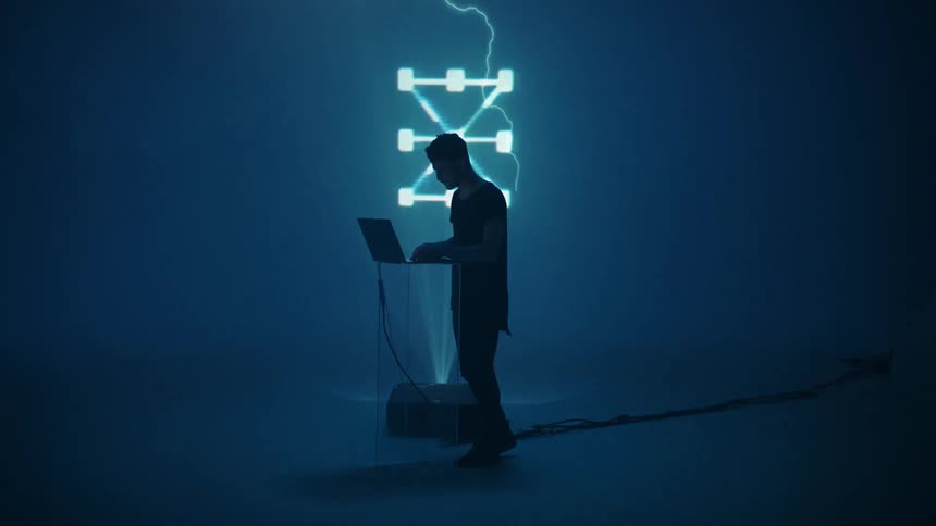 A man dances and sways to the music as he controls images projected with a laptop