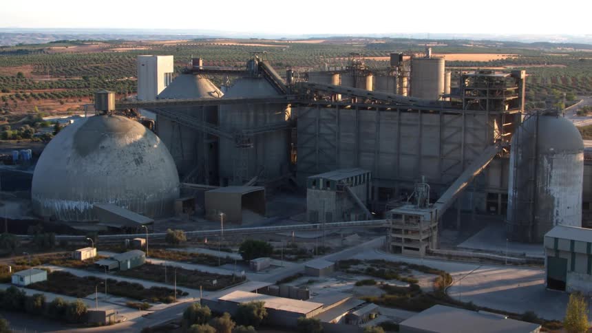 A factory with trees with the sky in the background