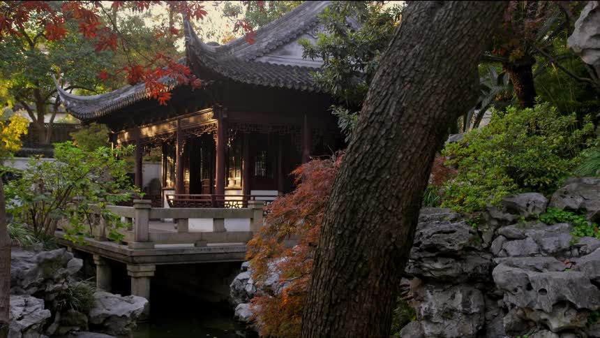 An asian style pagoda home on a pond surrounded by trees