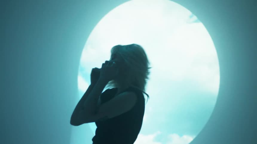Woman dances near cloudy sky projected onto wall