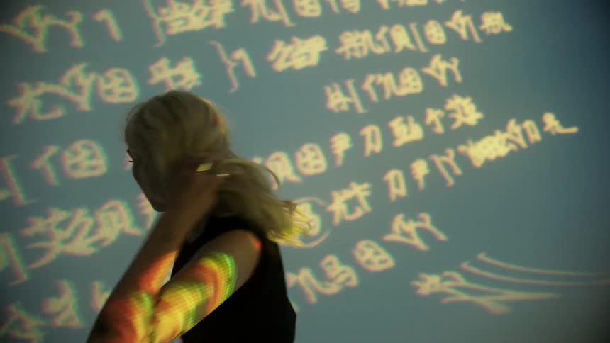 Blonde woman takes different poses in front of projected image