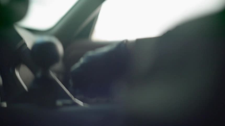 A person driving a car and shifting gears