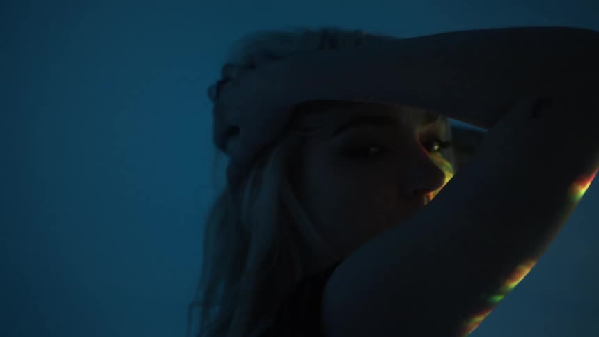 A woman models for the camera in front of flashing lights