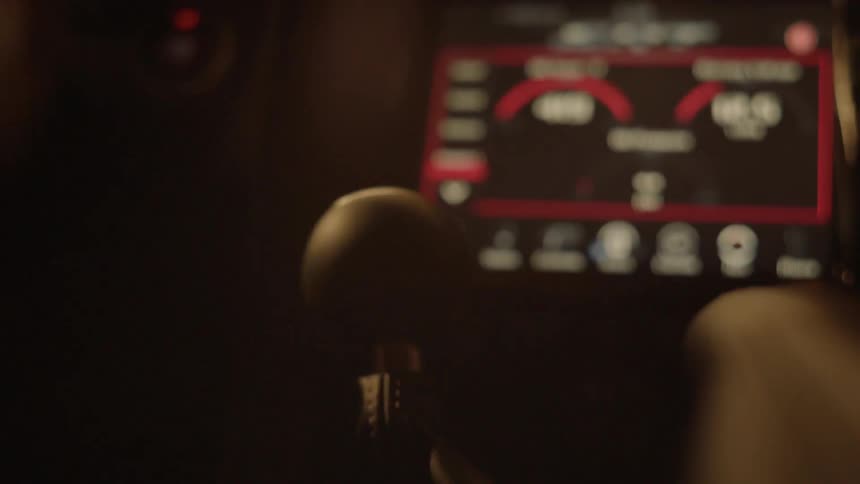 A driver wearing gloves shifts gears using the gear shift