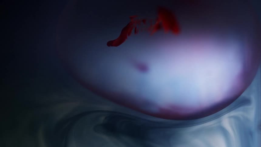 Red dye shape floats in a sphere of liquid