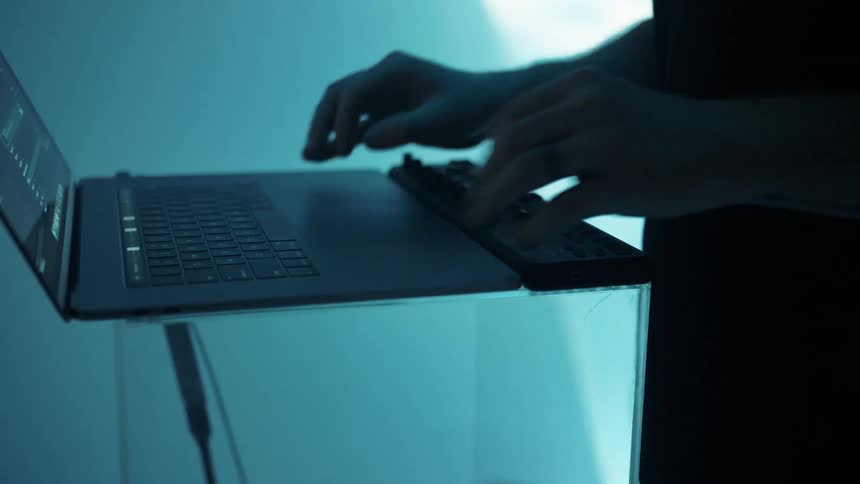 A man is using a laptop that sits upon an clear acrylic stand
