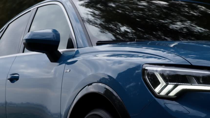 A blue car drives through a forest