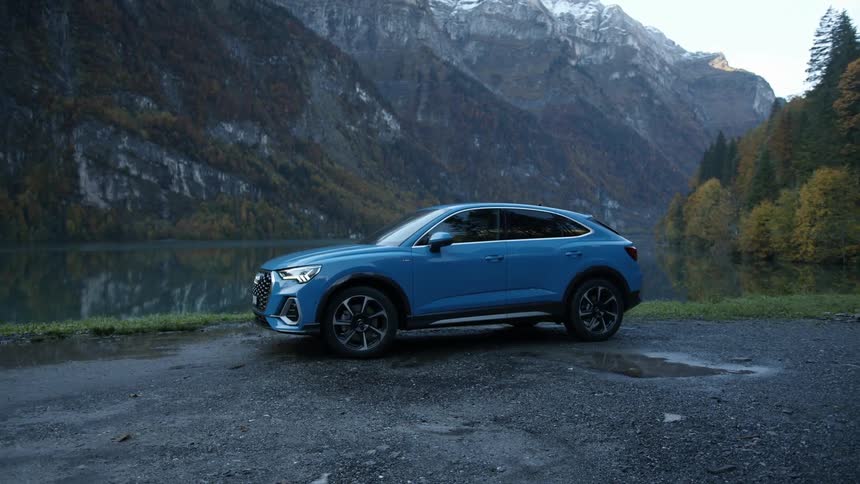 Blue car parked near a lake in the mountains