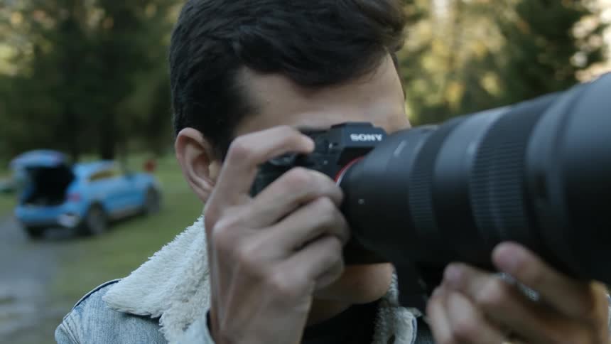 A photographer takes a photo outdoors with a large lens